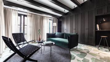 Een moderne woonkamer met een zwarte fauteuil, een groene bank en een ronde salontafel.