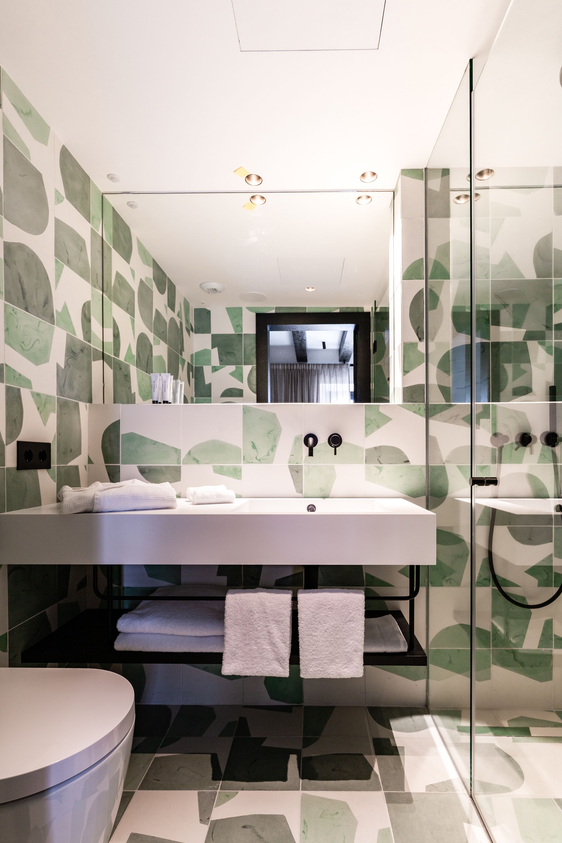 A modern bathroom with a large mirror, a white sink, and a glass shower enclosure.