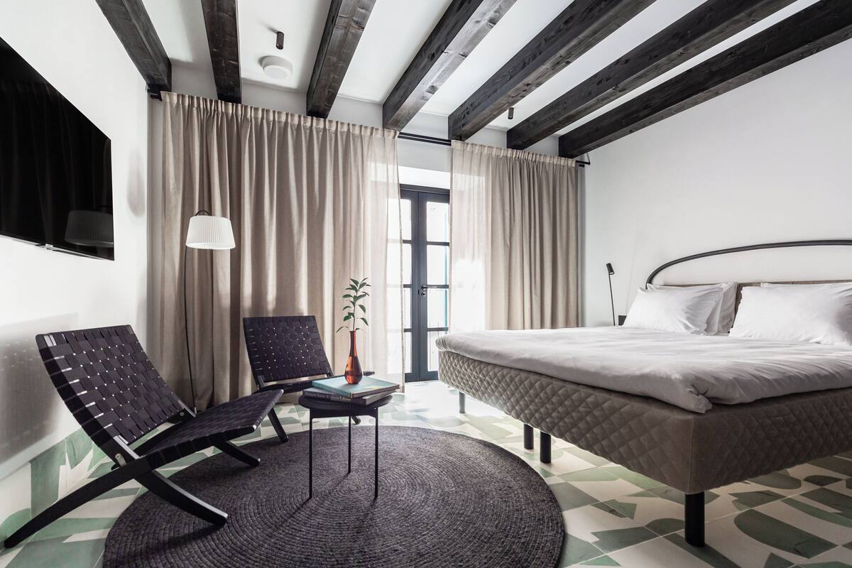Ein modernes Hotelzimmer mit Bett, Schreibtisch, Stuhl und einem Vorhangfenster.
