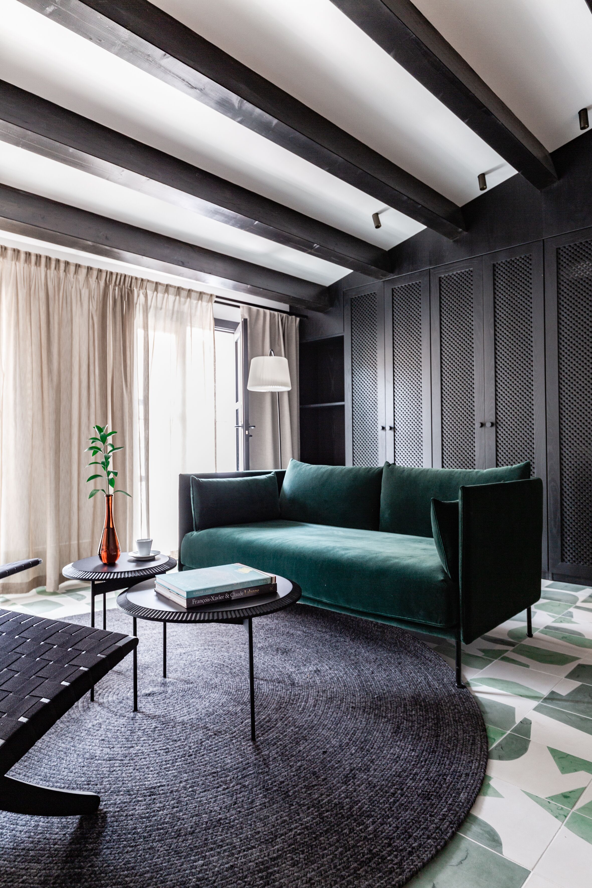 Una sala moderna con un sofá verde, una mesa de centro redonda y una alfombra estampada.