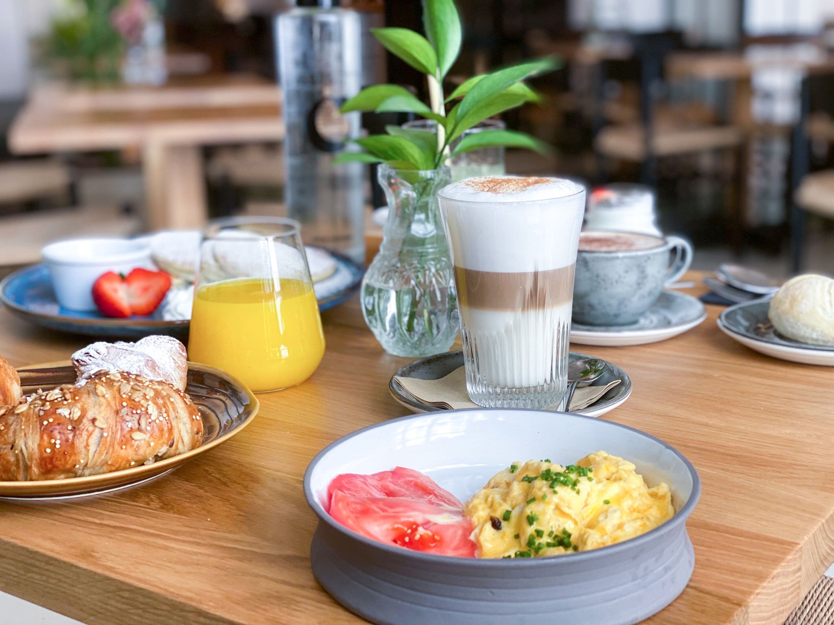 A breakfast table with croissants, scrambled eggs, and orange juice.