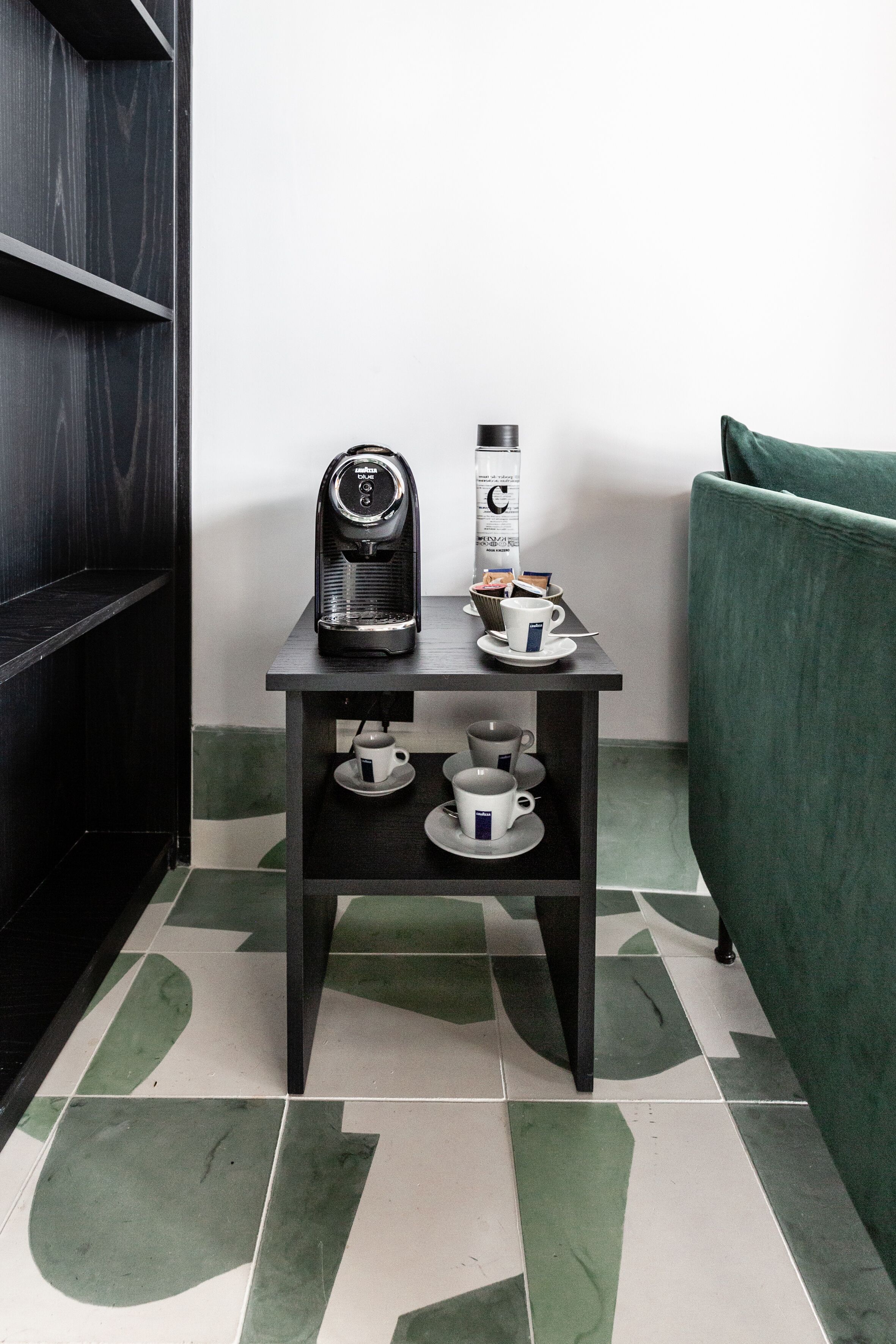 Una pequeña mesa con una cafetera, una taza de café y una caja de leche para café.