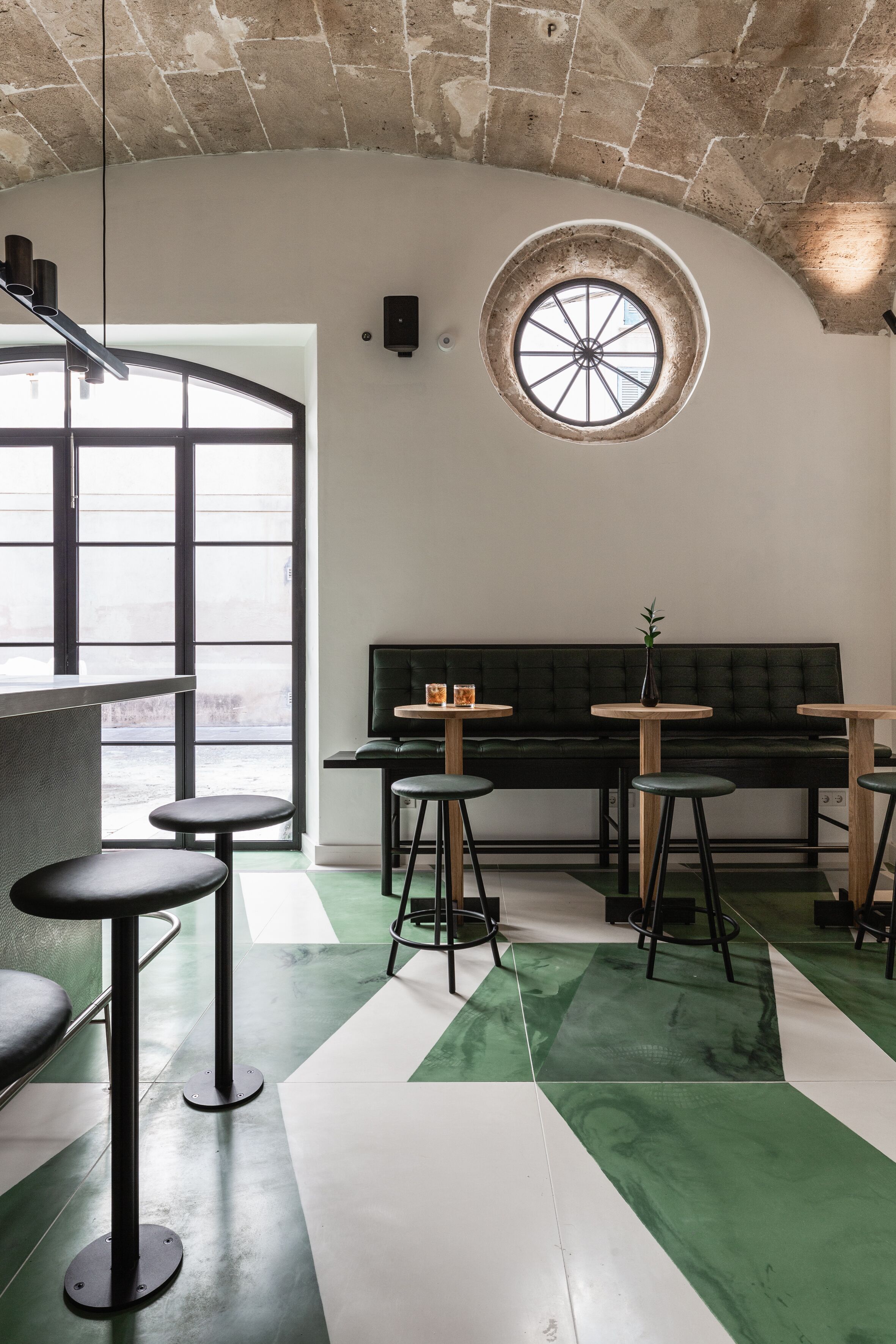 Ein modernes Interieur mit gewölbter Decke, einem großen Fenster und einem grün-weißen Fliesenboden.