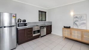 Una cocina moderna con un refrigerador de acero inoxidable, microondas, horno y lavavajillas.