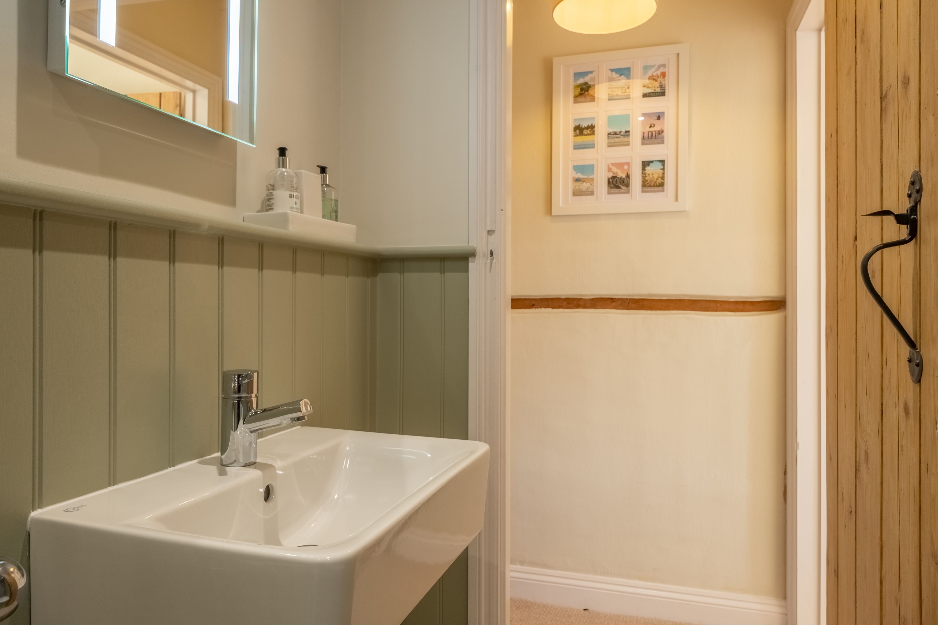 A bathroom with a white sink, a mirror, and a framed picture on the wall.