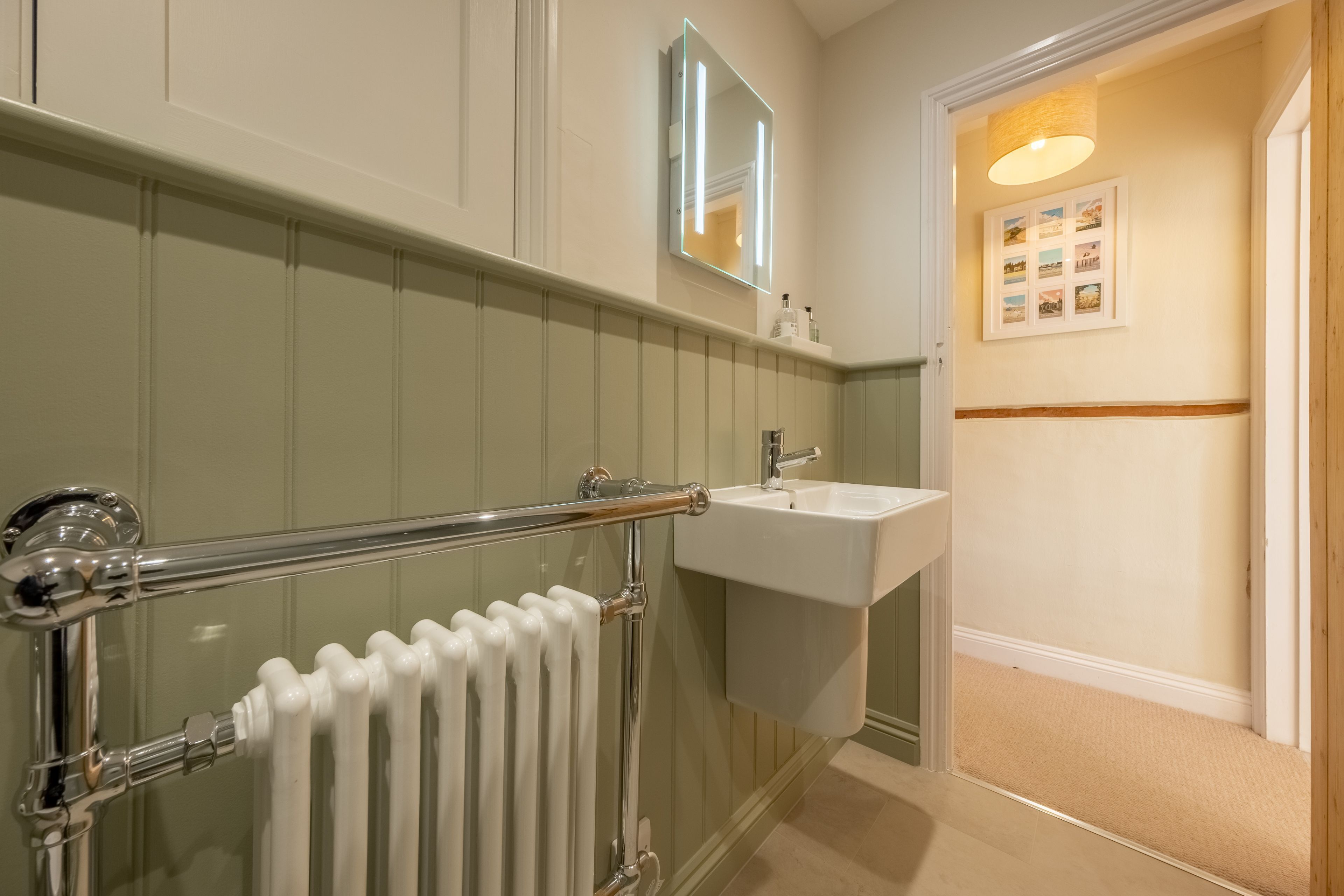 A bathroom with a bathtub, a sink, a mirror, and a radiator.