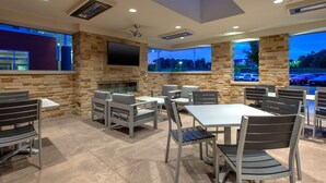 An outdoor dining area with stone walls, modern furniture, and a flat-screen TV mounted on the wall. - Hilton Garden Inn Columbus Easton (Columbus)
