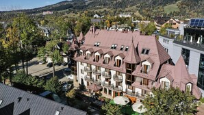 A multi-story building with a traditional architectural style, featuring multiple balconies and a central courtyard with outdoor seating. - Krupówki40 (Zakopane)