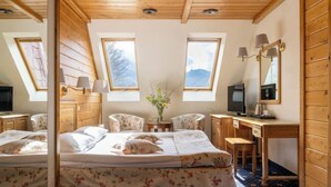 A bedroom with a bed, two chairs, a desk, a television, and a mirror. - Krupówki40 (Zakopane)