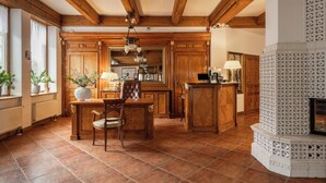 A spacious kitchen with wooden cabinets, a dining area with a table and chairs, and a decorative fireplace. - Krupówki40 (Zakopane)