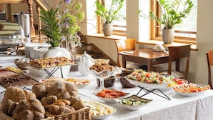 A buffet table with various food items and a wicker basket of bread. - Krupówki40 (Zakopane)