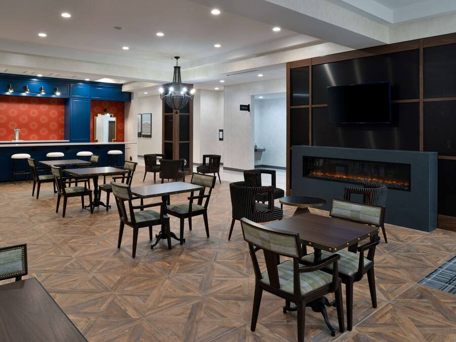 A spacious dining area with multiple tables and chairs, a bar area with stools, and a modern fireplace.