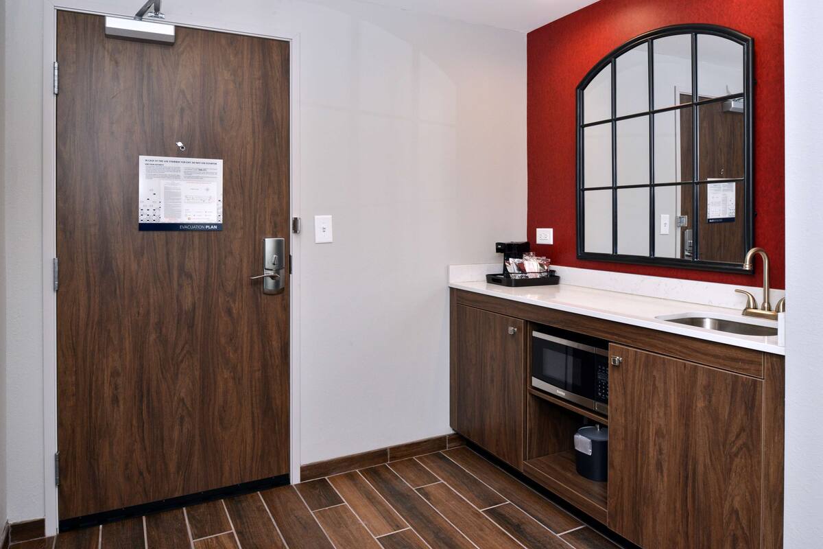 A kitchen with wooden cabinets, a microwave, and a sink.