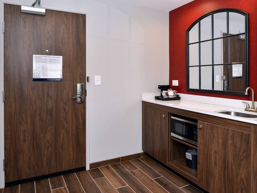 A kitchen with wooden cabinets, a microwave, and a sink.