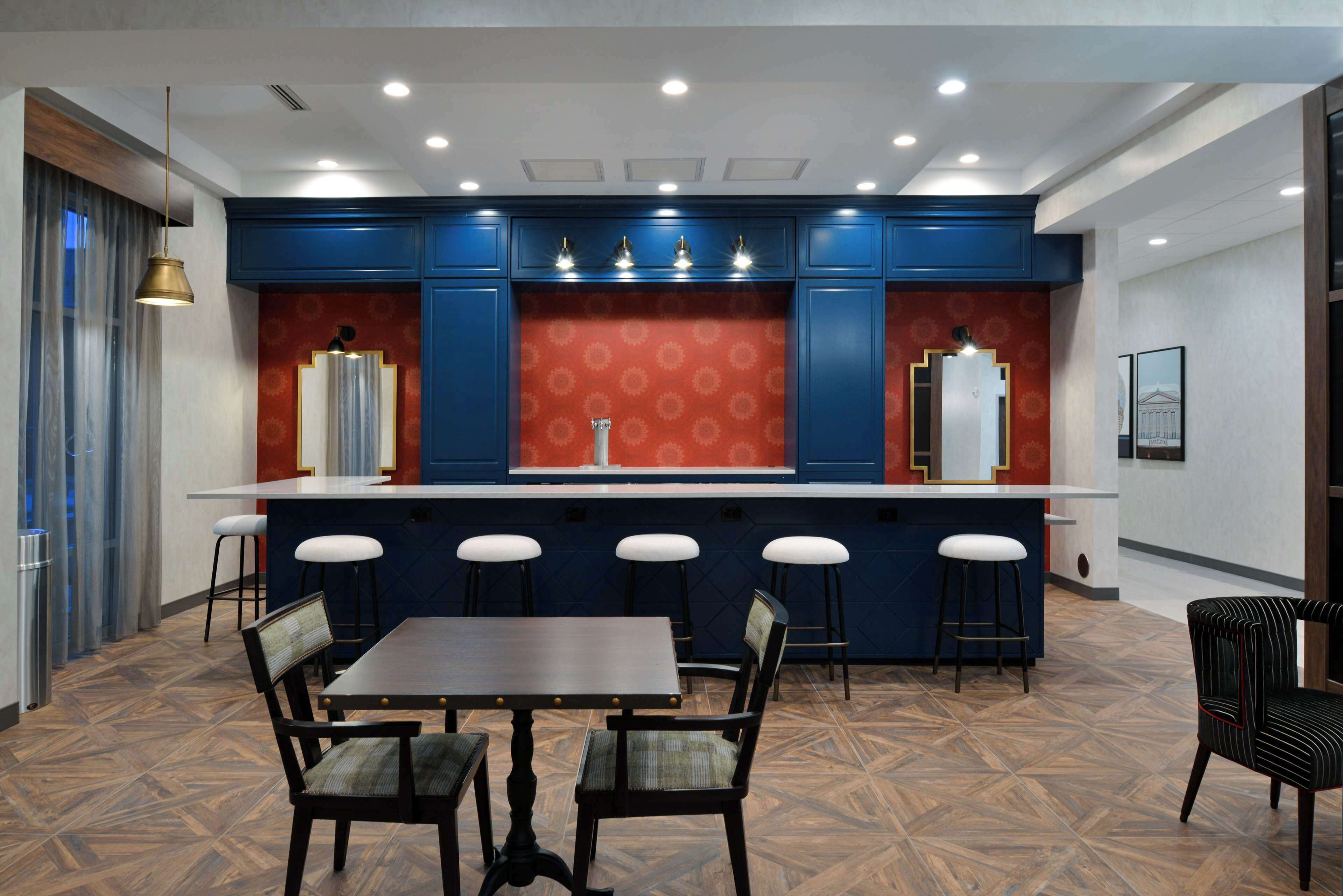 A modern kitchen with blue cabinets, a central island with stools, and a dining area with a table and chairs.