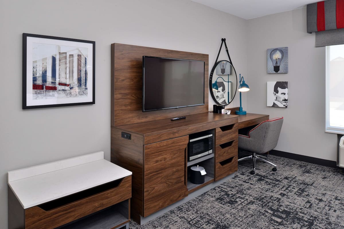 A modern office space with a wooden desk, a flat-screen TV, a chair, and artwork on the walls.