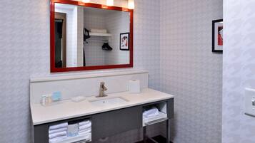 Une salle de bain avec un grand miroir, un lavabo et un porte-serviettes.