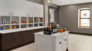 A kitchen with white cabinets, a minibar, and a minibar sign labeled "Hilton Honors". - Hampton Inn Indianapolis Downtown IUPUI (Indianapolis)