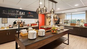 A modern kitchen with a central island, hanging pendant lights, and a blackboard with kitchen-related drawings. - Hampton Inn Indianapolis Downtown IUPUI (Indianapolis)