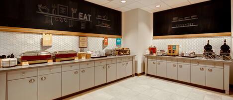 A breakfast bar with a variety of food items and a chalkboard menu.