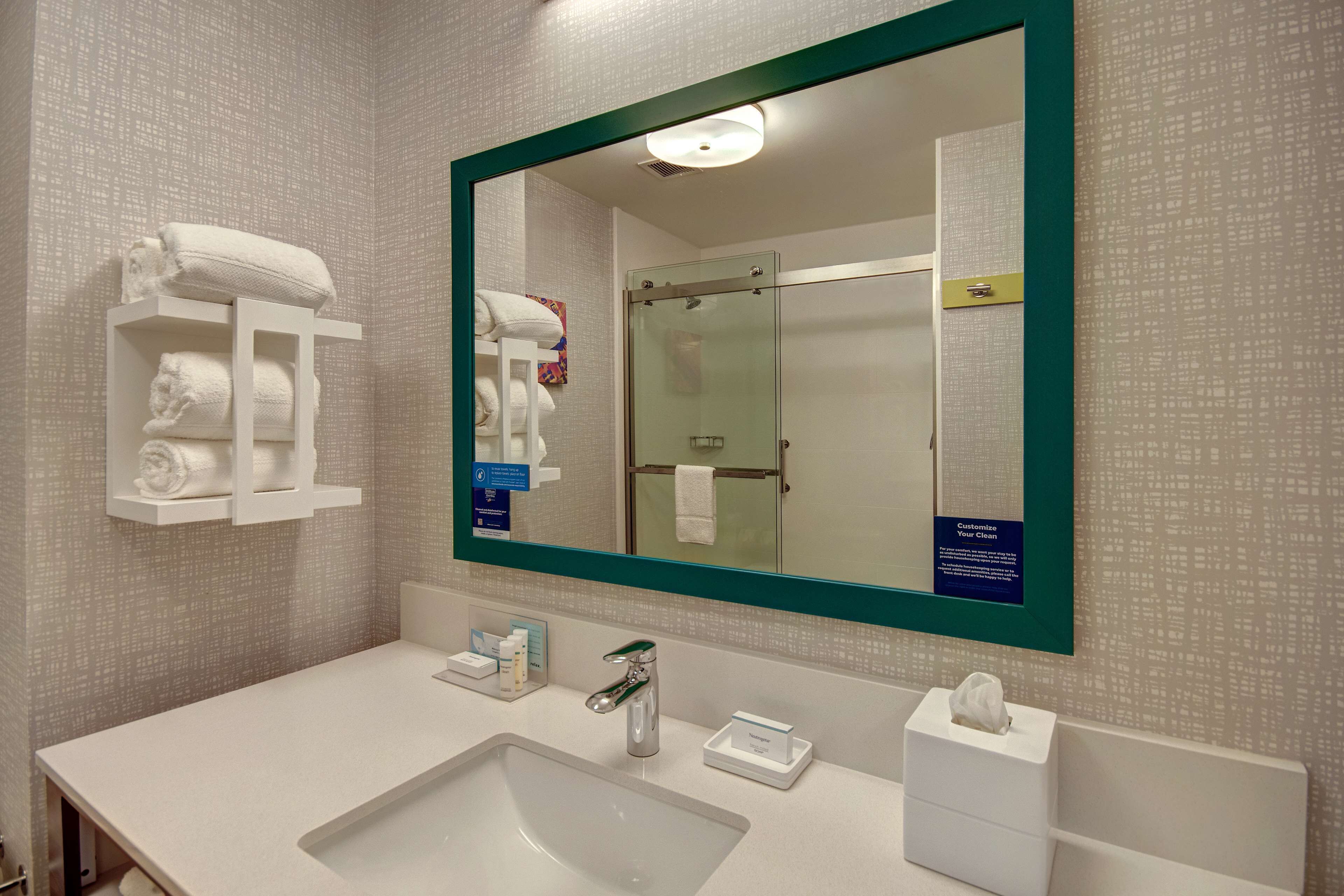 Un baño moderno con un espejo grande, un lavamanos y una cabina de ducha de vidrio.