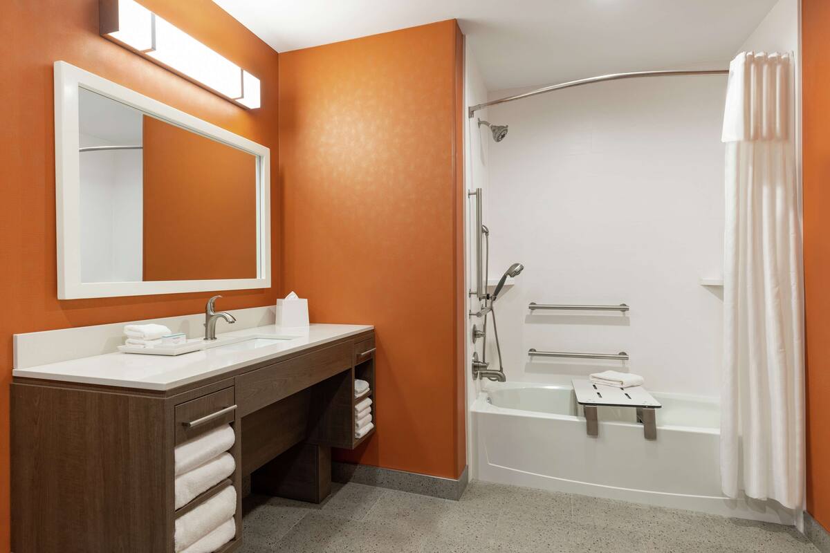 A bathroom with a white sink, mirror, and bathtub.