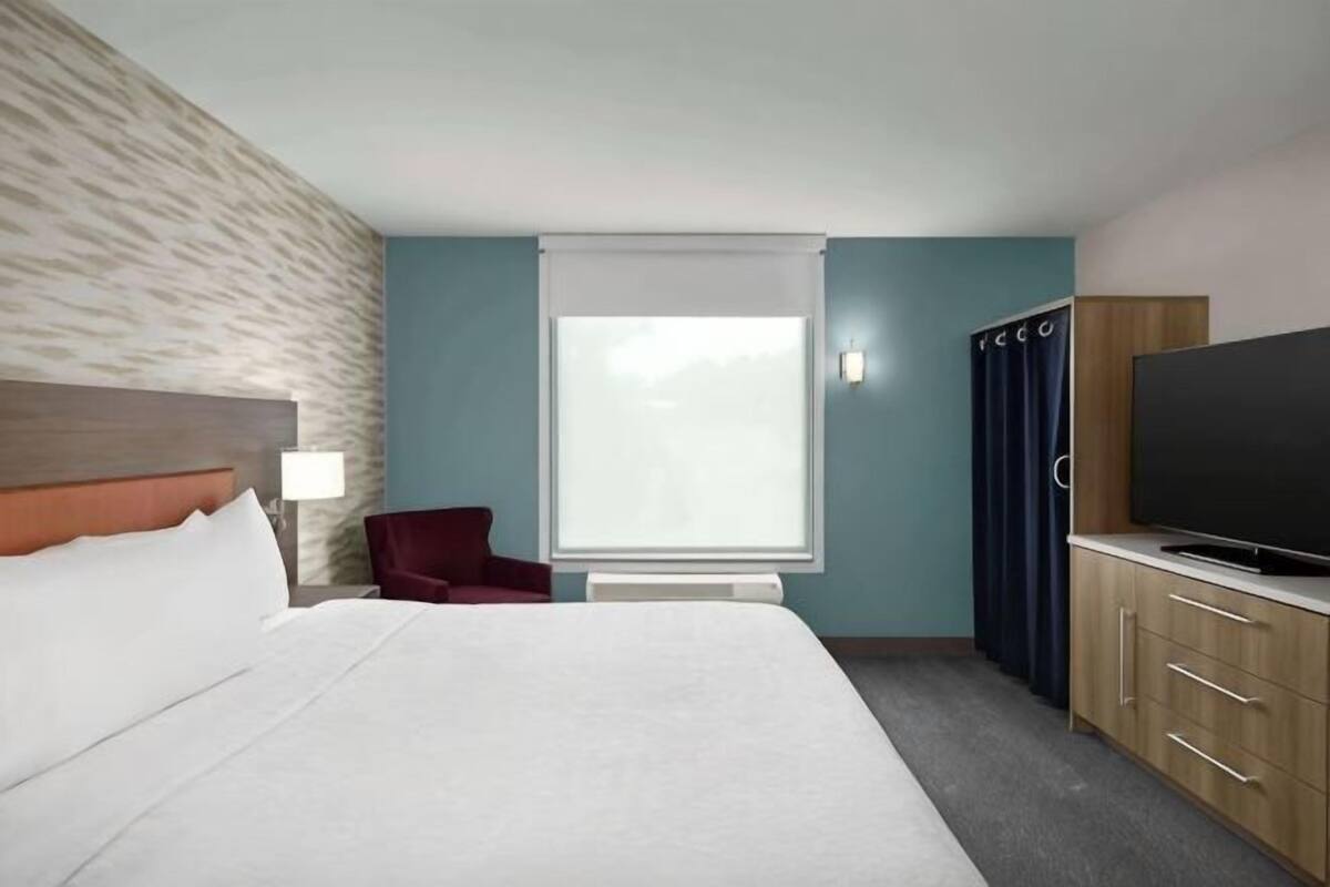 A hotel room with a bed, a TV, a desk, and a chair.