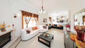 Un salón amplio con un sofá blanco, una mesa de centro negra y una chimenea.