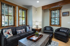 Un salon avec un canapé en cuir foncé, une table basse en bois et deux fauteuils en cuir.