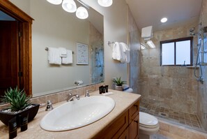 Une salle de bain moderne avec un grand lavabo, un miroir, une douche et des toilettes.