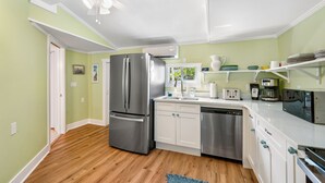 Una cocina moderna con electrodomésticos de acero inoxidable, armarios blancos y piso de madera.