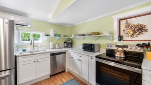 Una cocina moderna con armarios blancos, electrodomésticos de acero inoxidable y salpicadero de azulejos.