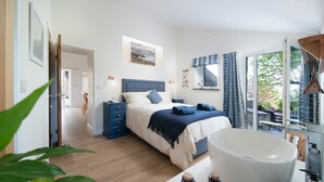 A modern bedroom with a large bed, a nightstand, a dresser, and a bathroom with a white basin and sink. - A luxury rural retreat, Barnstaple, perfect for couples and families, set in glorious North Devon (Barnstaple)