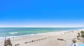 Un complejo turístico en la playa con piscina, sillas de playa y una torre de salvavidas.