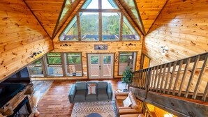 Um amplo quarto em estilo loft, com teto alto, paredes de madeira e grandes janelas que oferecem vista para o exterior.
