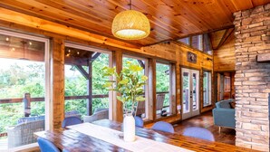 Interior em madeira com mesa de jantar, cadeiras e luminária pendente.