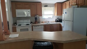 Une cuisine avec des meubles de rangement en bois, une cuisinière blanche, un four à micro-ondes, un évier et un réfrigérateur.