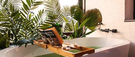 Una bañera con una bandeja de madera, un libro y una copa de vino.