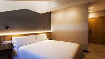 A modern hotel room with a large bed, a wooden headboard, a nightstand, and a wooden door.