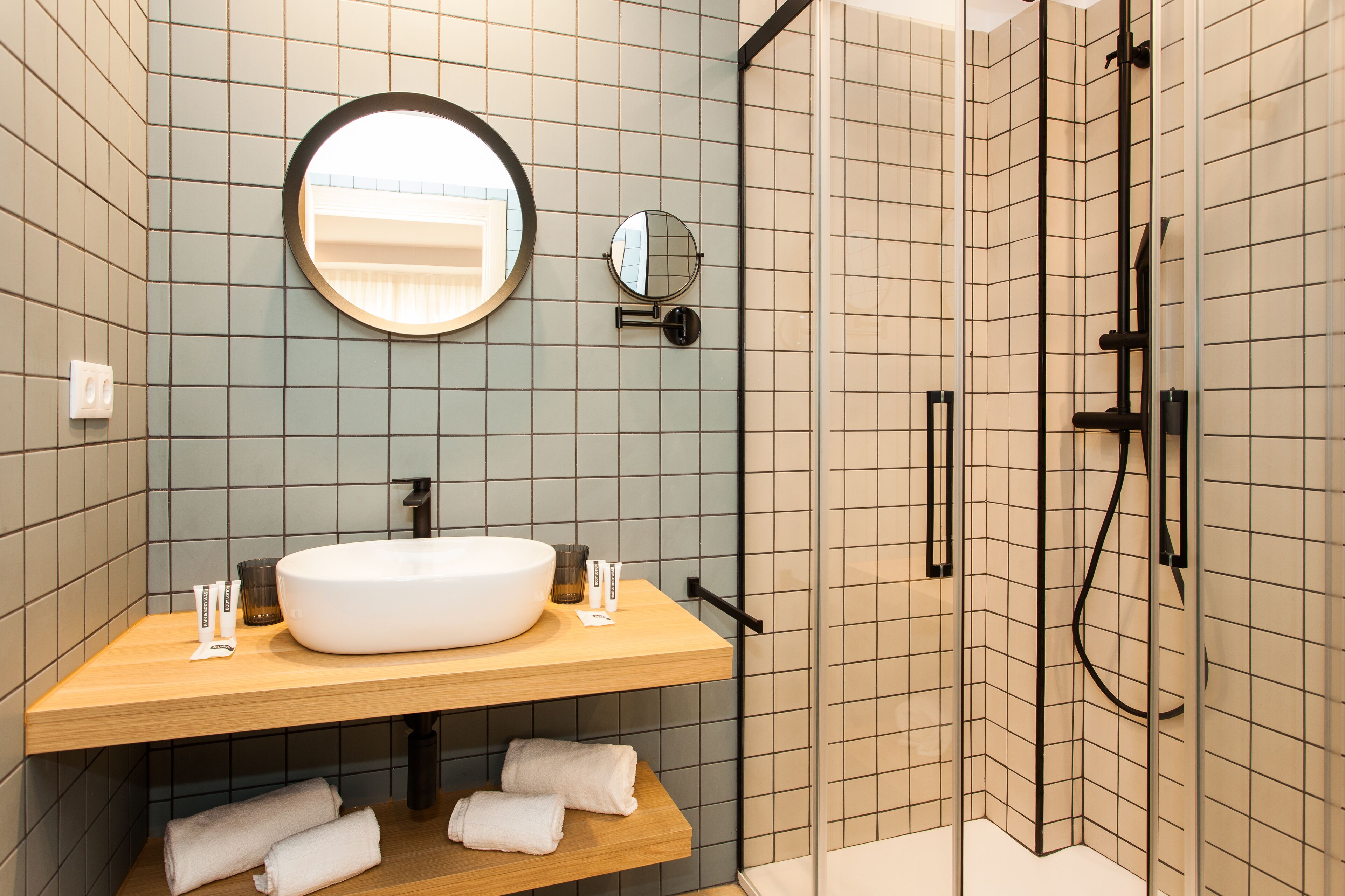 A modern bathroom with a round mirror, a white sink, and a shower area.