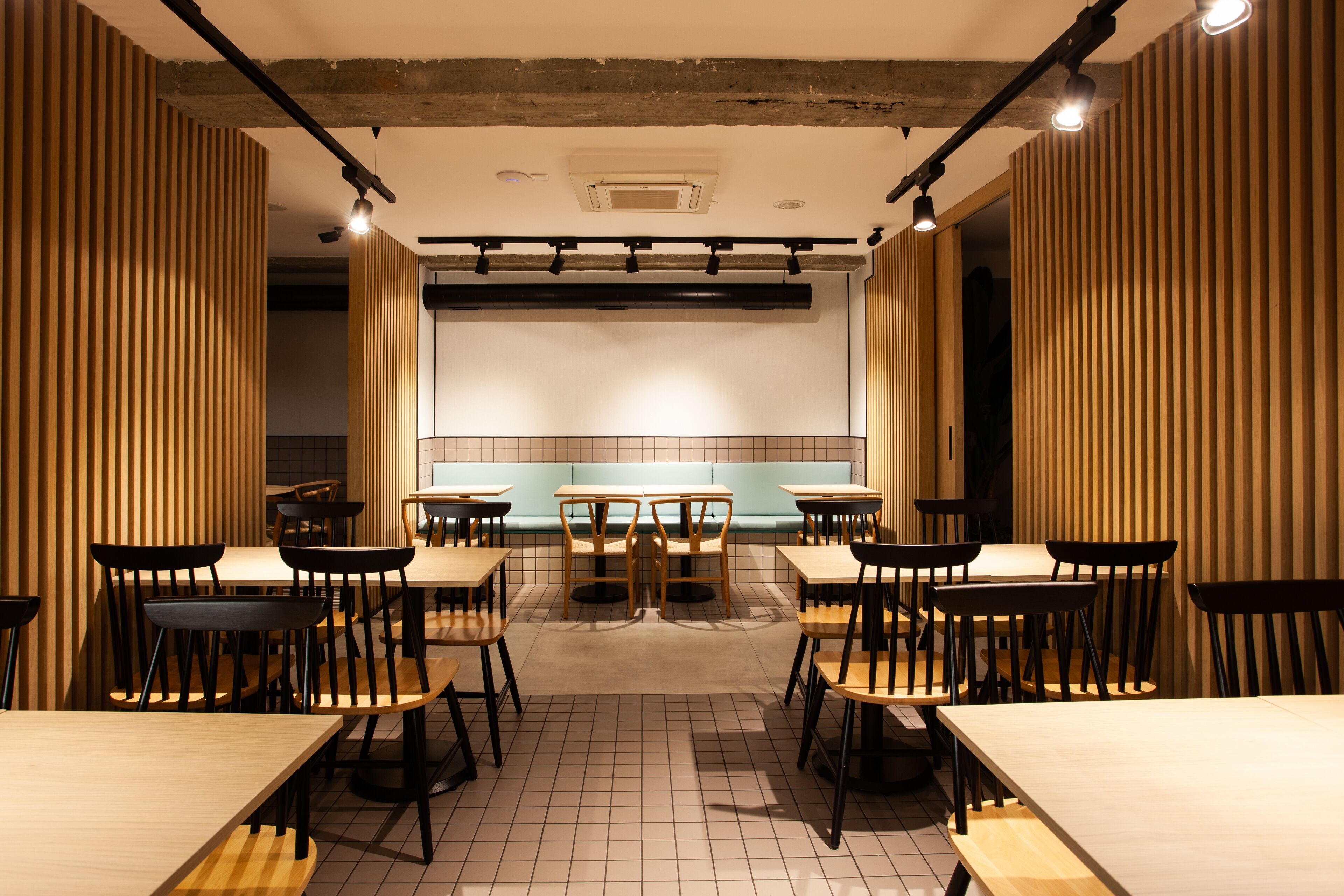 Un interior de restaurante con paredes de paneles de madera, suelo de baldosas y varias mesas y sillas.