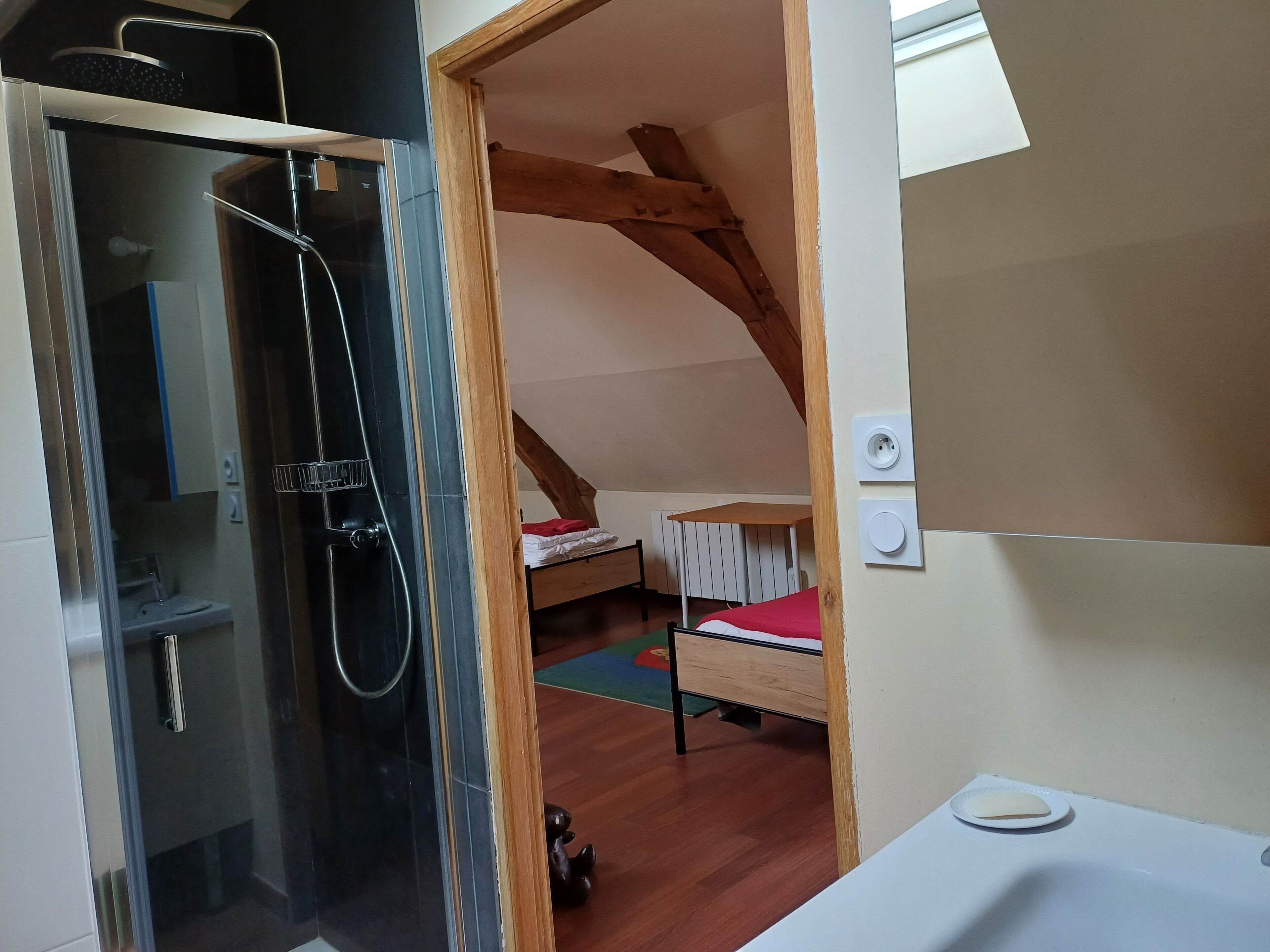 A small, cozy room with a shower, a bed, and a window.