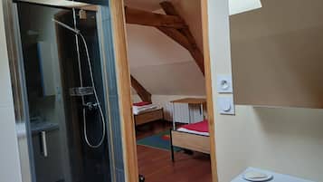 A small, cozy room with a shower, a bed, and a window.