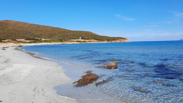 A beach with clear shallow waters, a sandy shore, and a hill in the background. - T2 neuf-VUE MER-CLIMATISE-WIFI-PISCINE- 4 personnes-Classé 3*** (Linguizzetta)