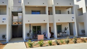 A multi-story residential building with balconies, air conditioning units, and a small garden area. - T2 neuf-VUE MER-CLIMATISE-WIFI-PISCINE- 4 personnes-Classé 3*** (Linguizzetta)