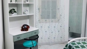 A bedroom with a desk, chair, wardrobe, and a bed with a green blanket. - La Casetta di Angela - Bilocale (Marsala)