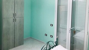 A room with a teal wall, a wooden wardrobe, and a sliding glass door. - La Casetta di Angela - Bilocale (Marsala)
