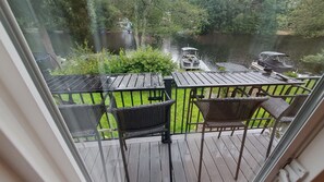 Enjoy a serene view of the backyard from this balcony with a wooden deck and comfortable seating for two.