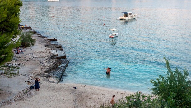 A coastal scene with a sandy beach, calm water, and boats. - Modern apt w. Terrace, 2 min Walk to the Beach (Okrug)