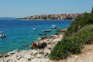 A coastal scene with rocky terrain, clear blue waters, and boats. - Modern apt w. Terrace, 2 min Walk to the Beach (Okrug)